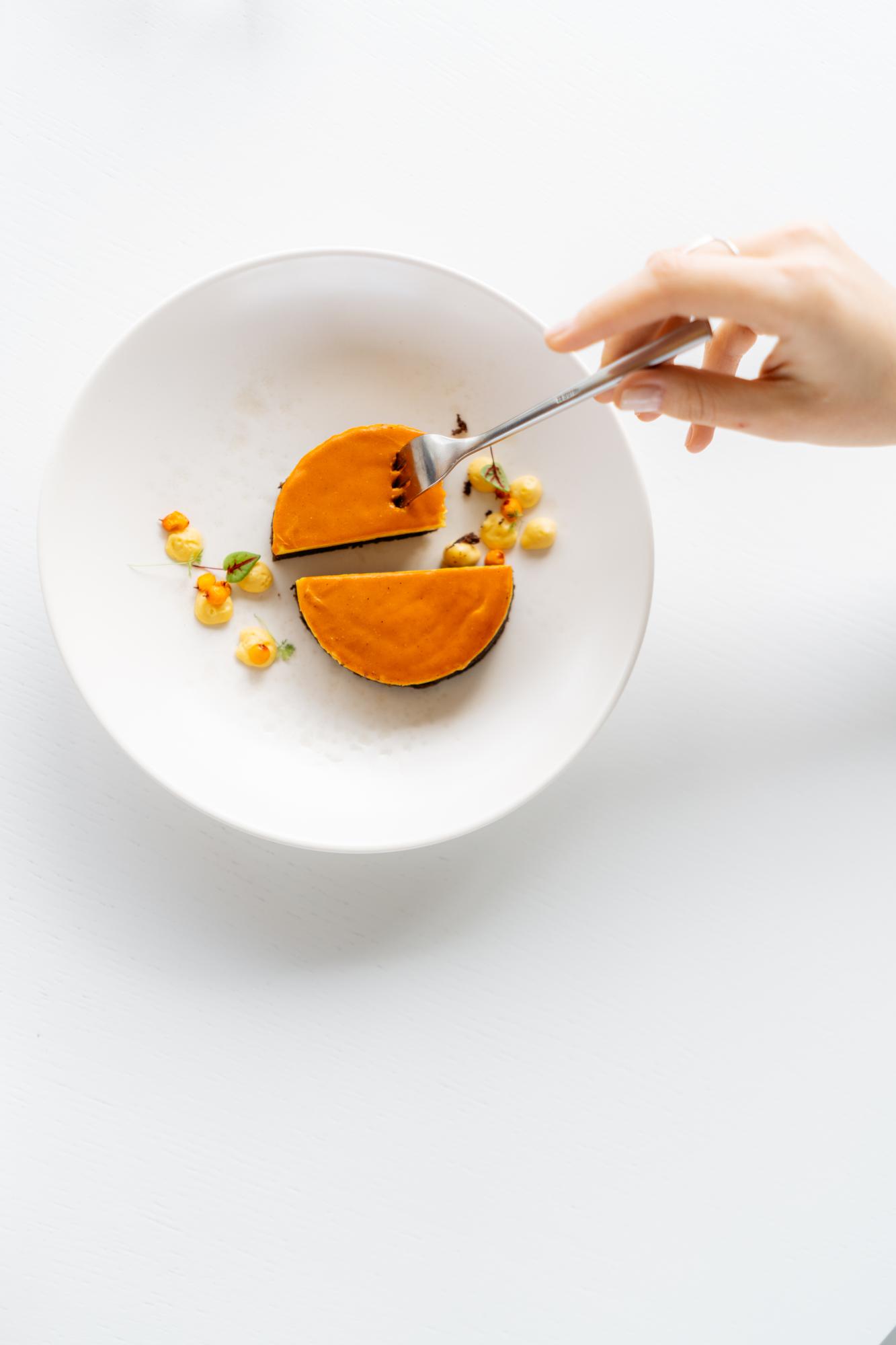 Hands finishing a plated dessert in studio